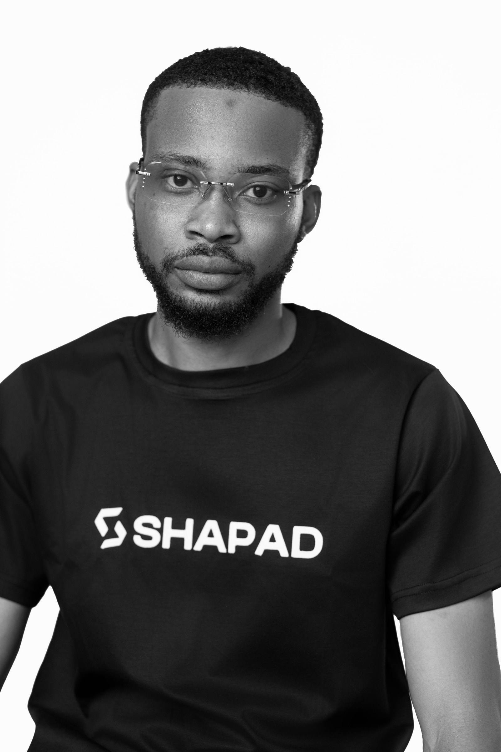 Member of the Shapad team in a black SHAPAD t-shirt looking at the camera, black-and-white studio portrait